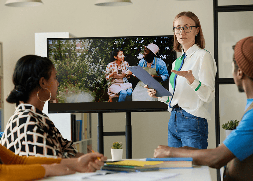 Young female teacher showing videos to group of students